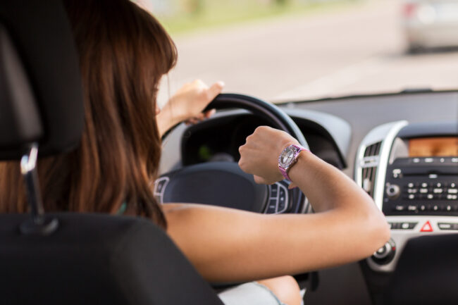 woman driving a car and looking at watch