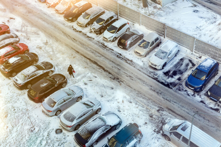Top view of parking full of cars covered by snow in early winter morning